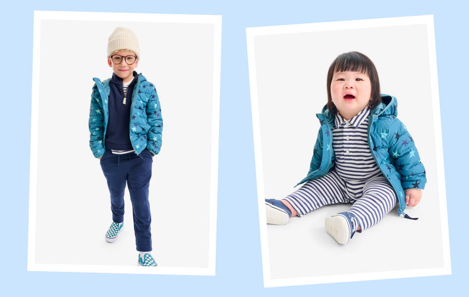 A kid and a baby sitting on the ground wearing a matching blue star puffer jackets