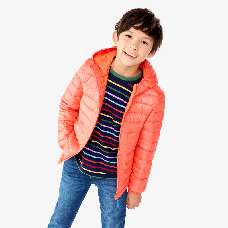 An image of a boy smiling wearing an orange color puffer jacket